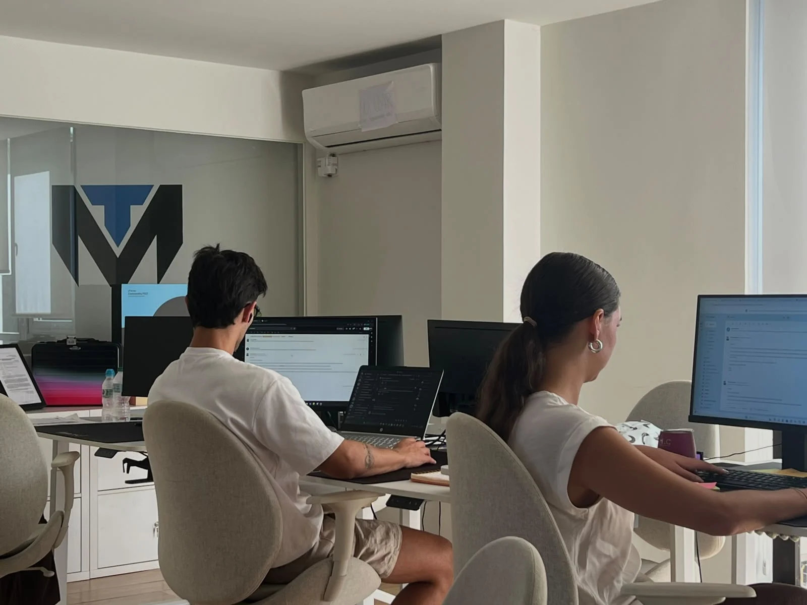 The team working in the office, with the TuManag3r logo in the background