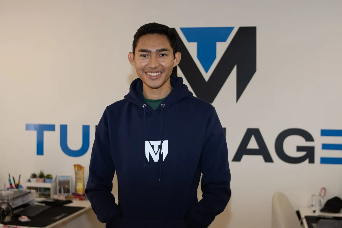 Fernanfloo in front of the TuManag3r logo at the office