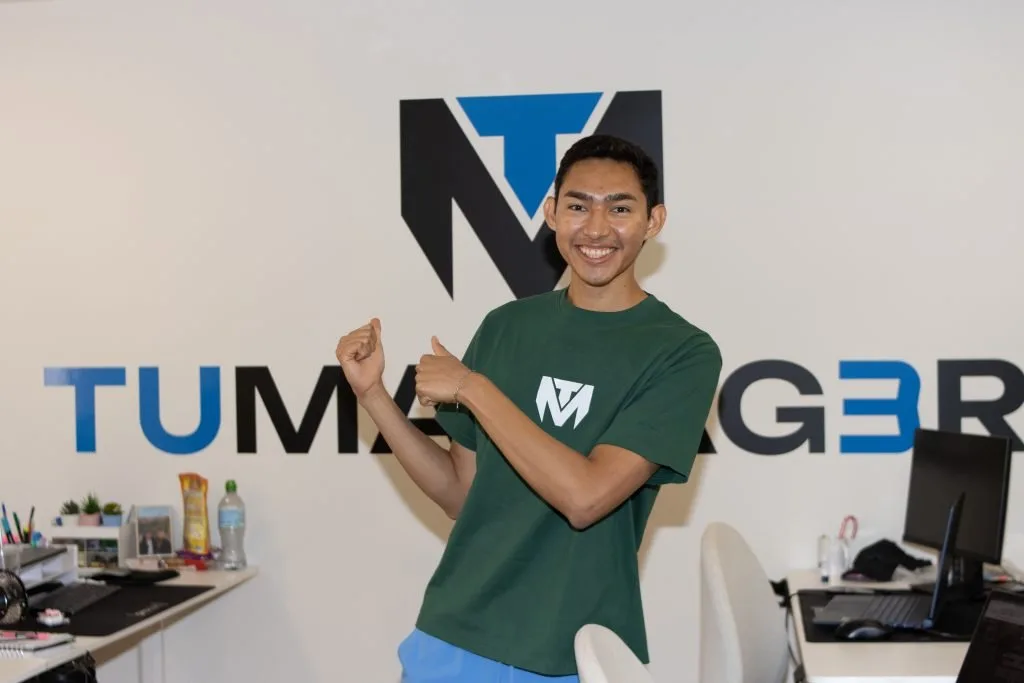 Creator in a TuManag3r shirt poses in front of the agency logo